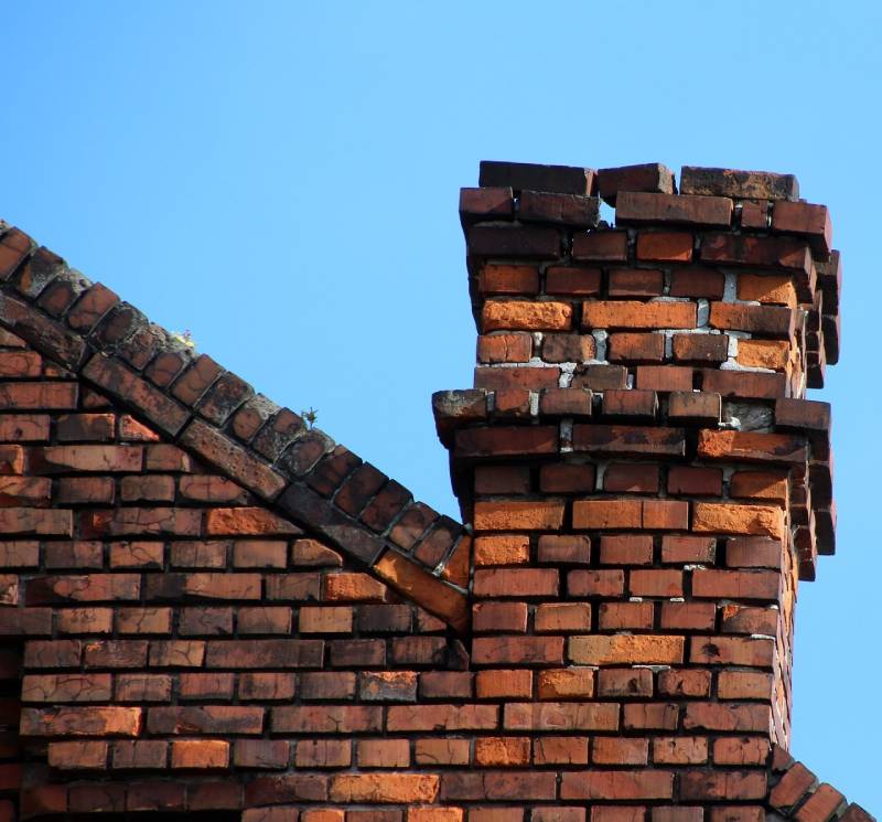 Damaged chimney on an Alexandria home showing cracks and missing mortar